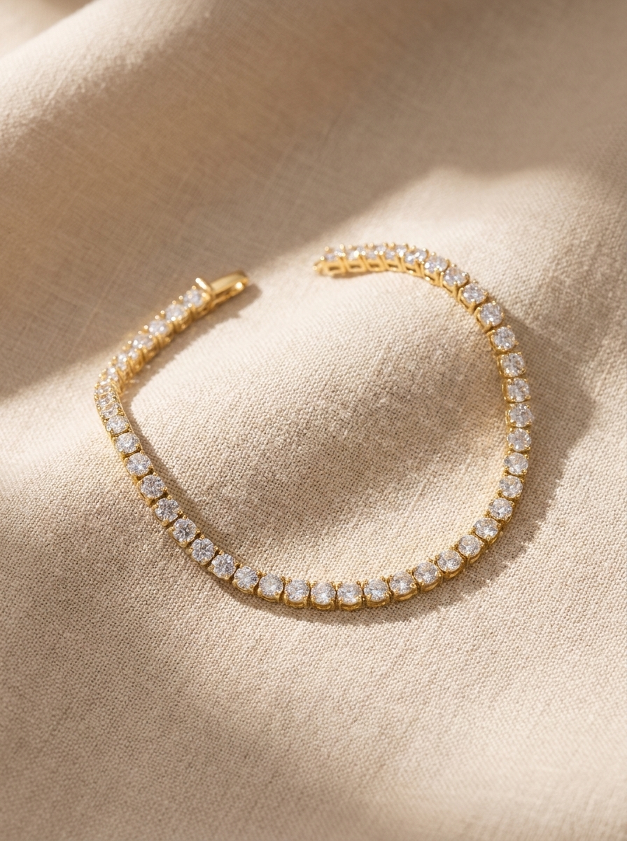 Bracciale tennis con zirconi color oro adagiato su lino